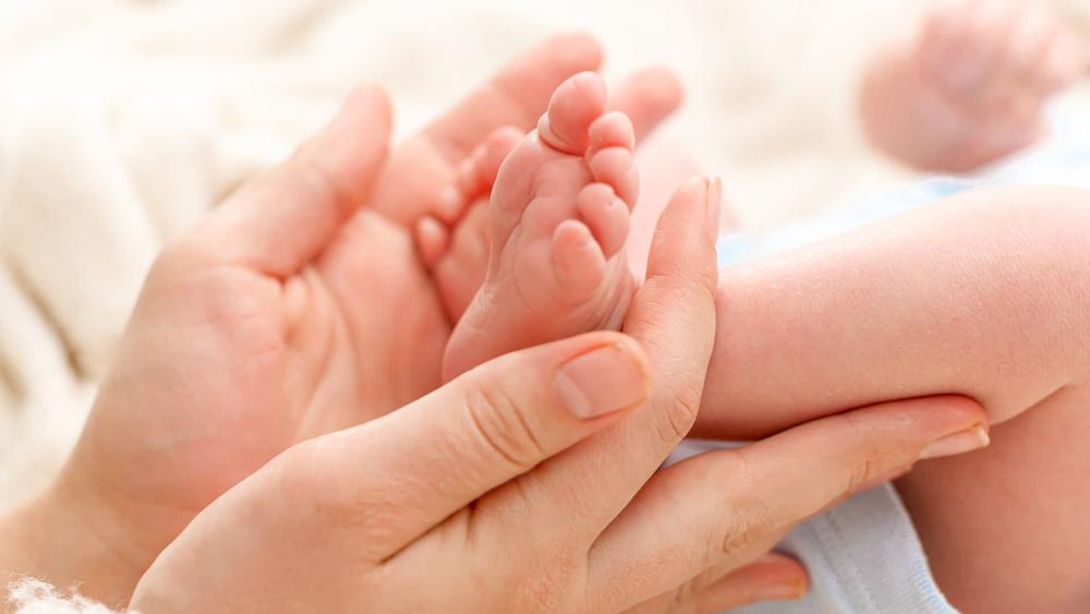 Poza generala un piciorus de bebe si mainile unei femei care il tin