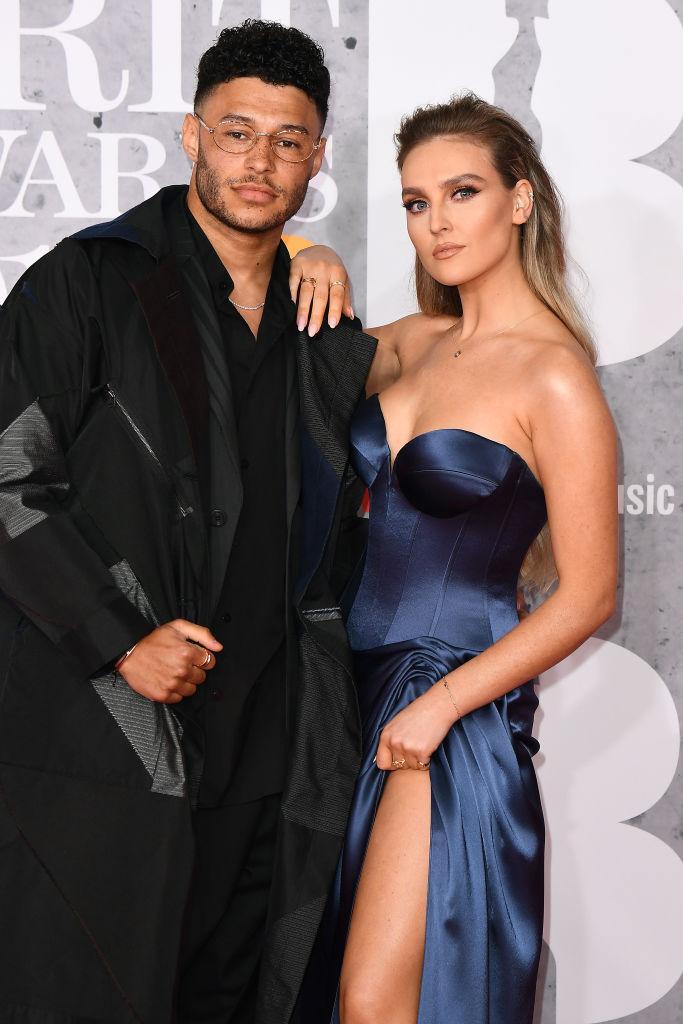 Perrie Edwards, imbracata intr-o rochie bleumarin din satin, și iubitul ei, fotbalistul Alex Oxlade, imbracat in negru