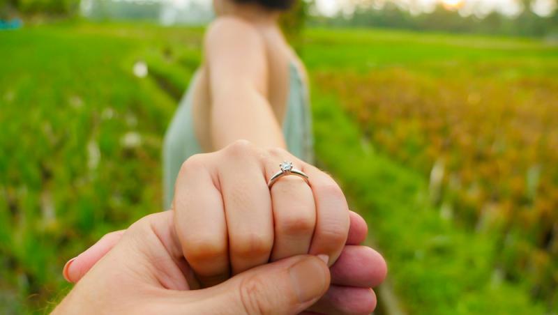 imagine cu mana unei tinere care poarta un inel de logodna