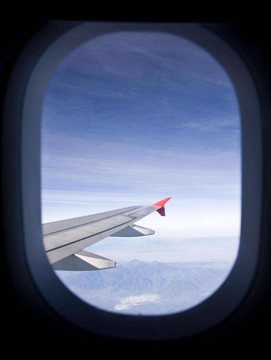 fereastra rotunda din avion prin care se vede cerul si o parte din avion
