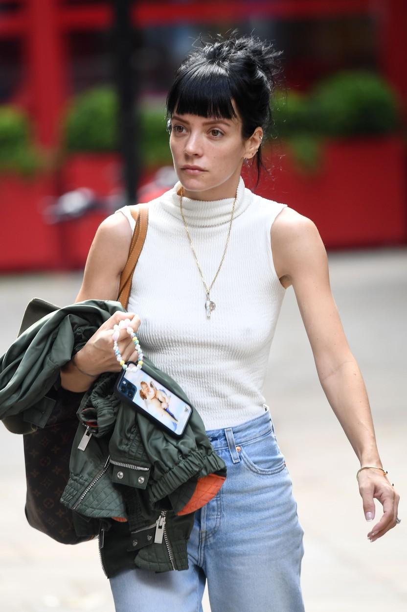 lily allen intr-un top alb, blugi albastri lungi si parul prins