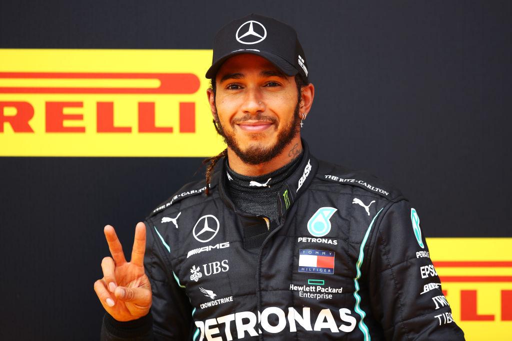 Lewis Hamilton în echipament negru, zâmbește