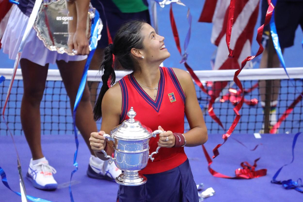 Emma Răducanu ține trofeul în mână și zâmbește pe terenul de tenis