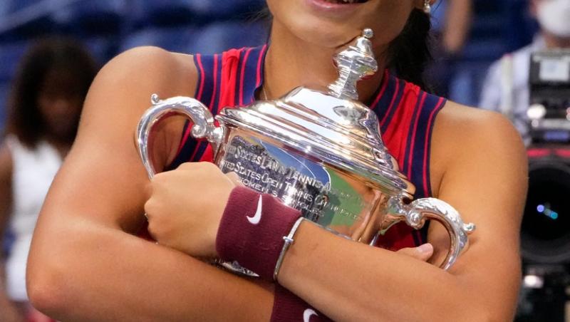 Emma Răducanu zâmbește și ține trofeul în brațe