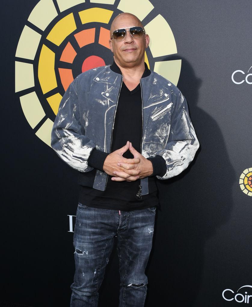 Vin Diesel, imbracat intr-o geaca din blugi si pantalongi din blugi, cu ochelari de soare la ochi