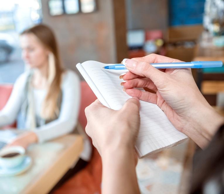 imagine cu o chelneriță in timp ce scrie un bilet