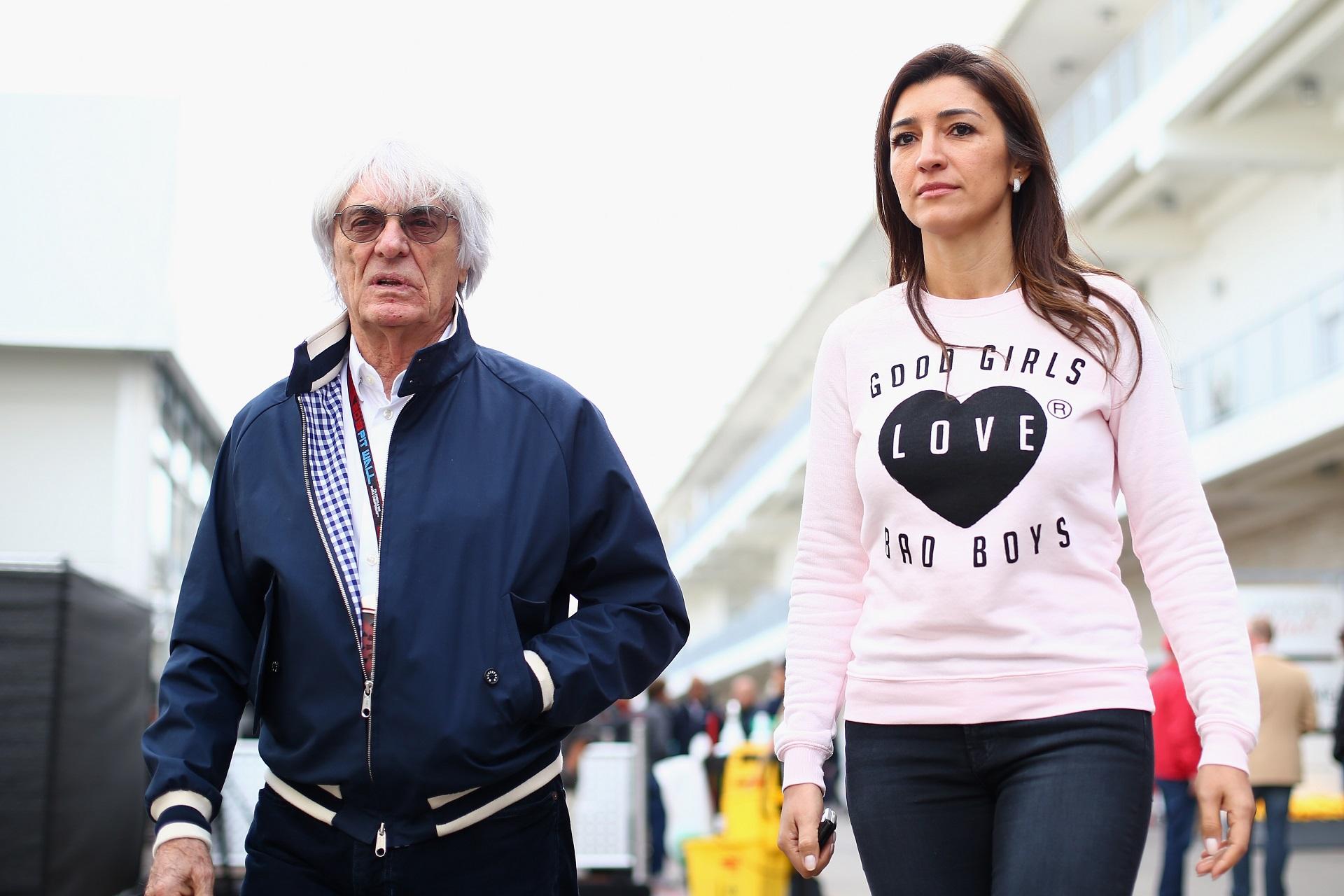 bernie ecclestone și a treia soție, fabiana flosi, la curse. el poartă o haină albastră, bluză albă, ea poartă un tricou roz