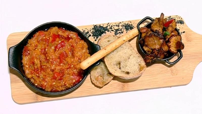 Zacuscă de vinete cu gălbiori, prezentată într-un bol pe un platou de lemn, alături de legume coapte