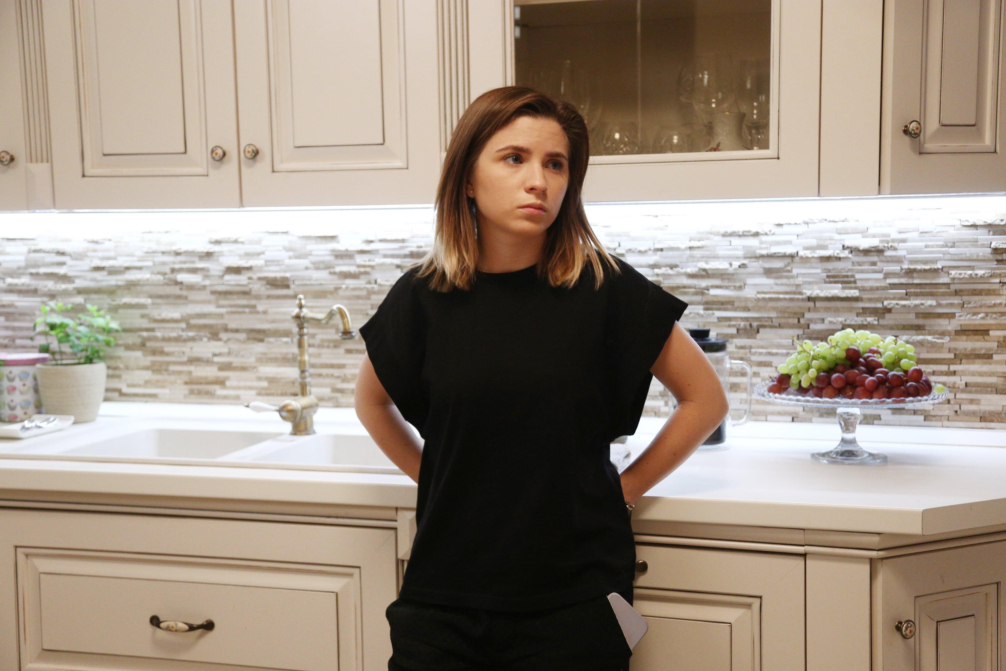 Livia, în casa Andronic, sprijinită de blatul din bucătărie și îmbrăcată în negru
