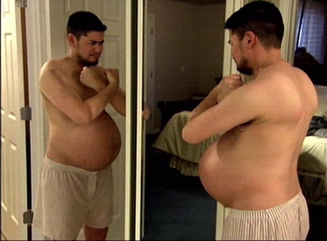 Thomas Beatie, cu burta de gravid, privindu-se în oglindă