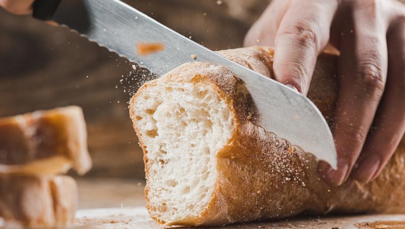 O fotografie cu o pâine care este feliată cu un cuțit.