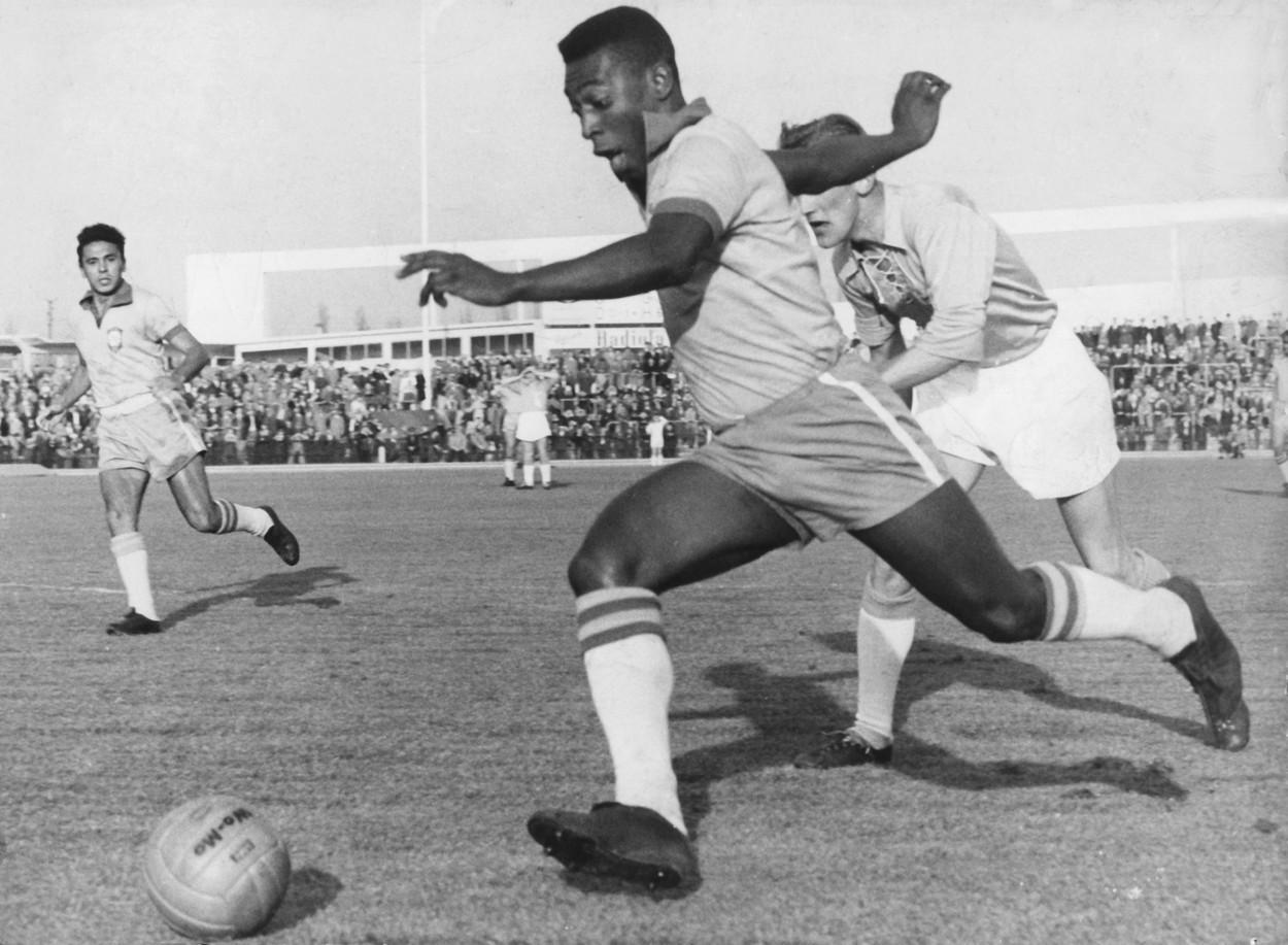 pele pe terenul de fotbal in timp ce e alergat de un adversar