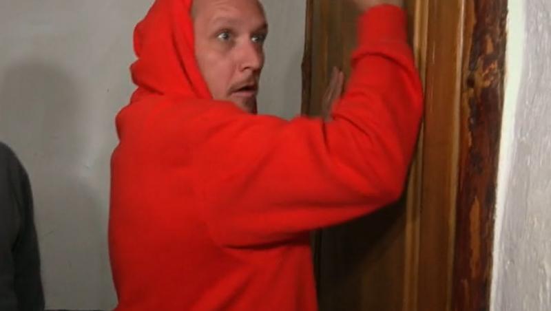 What's UP, într-un hanorac roșu, lângă ușă