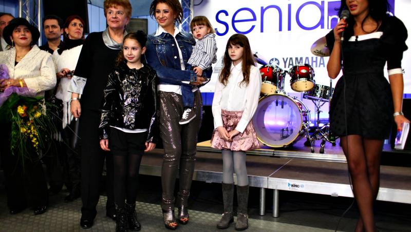 Anamaria Prodan alături de familia ei, impresara poartă o pereche de pantaloni roz lucioși, o geacă de blugi și o cămașă albă