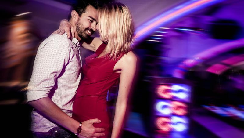 femeie si barbat danseaza imbratisati in club