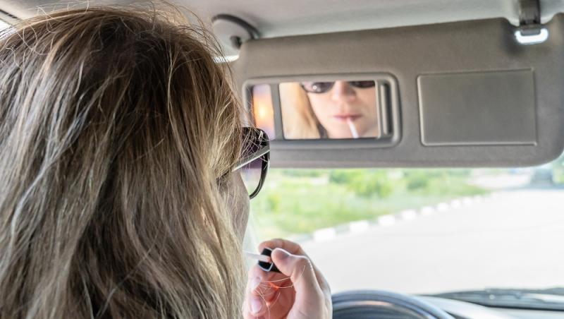 femeie uitandu-se in oglinda unei masini