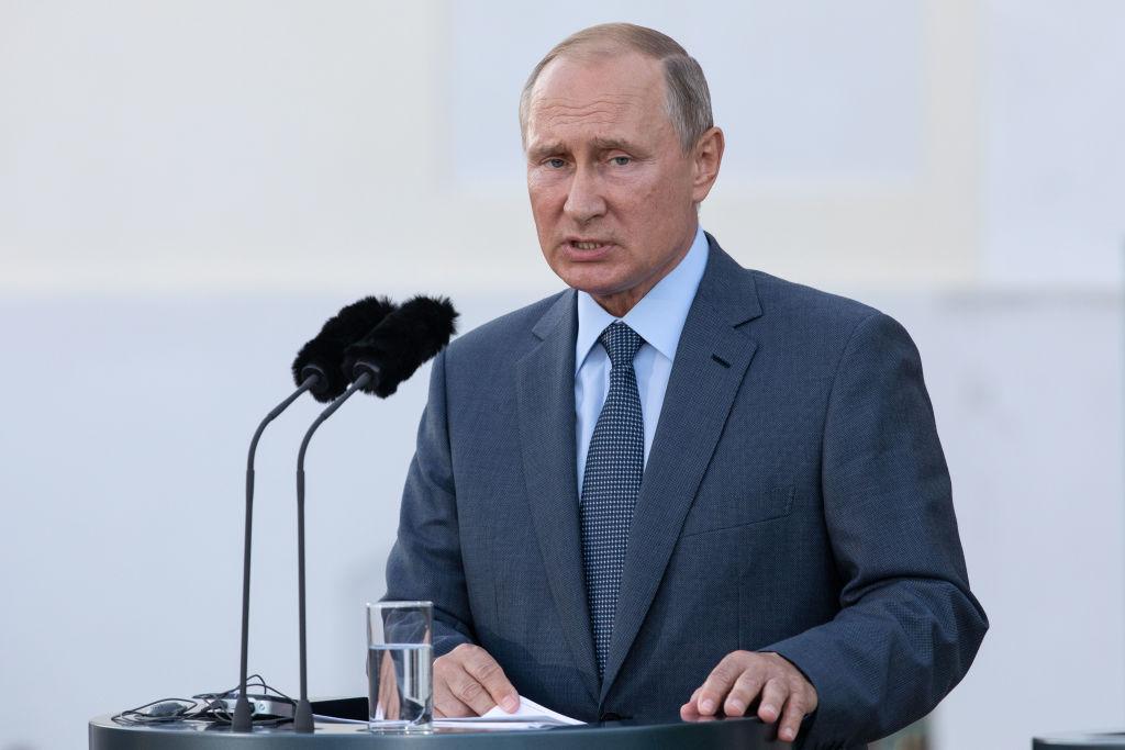 Vladimir Putin în costum gri, vorbește la microfon