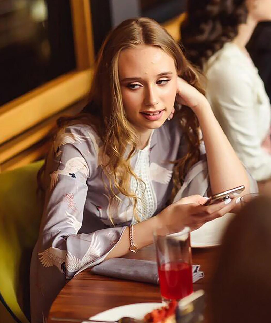 luiza rozova cu un telefon in mana in timp ce sta la o masa