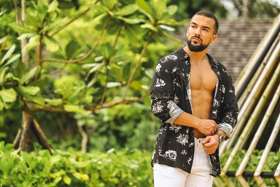 Cristian Grigorescu, purtând o cămașă desfăcută, în fața unor palmieri, la Insula Iubirii