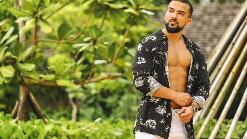 Cristian Grigorescu, purtând o cămașă desfăcută, în fața unor palmieri, la Insula Iubirii