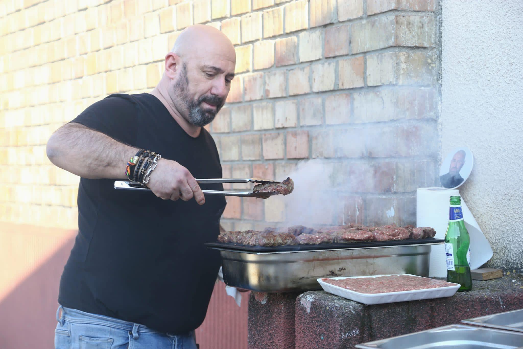 Chef Scărlătescu  face mici pe grătar, îmbrăcat într-un tricou negru