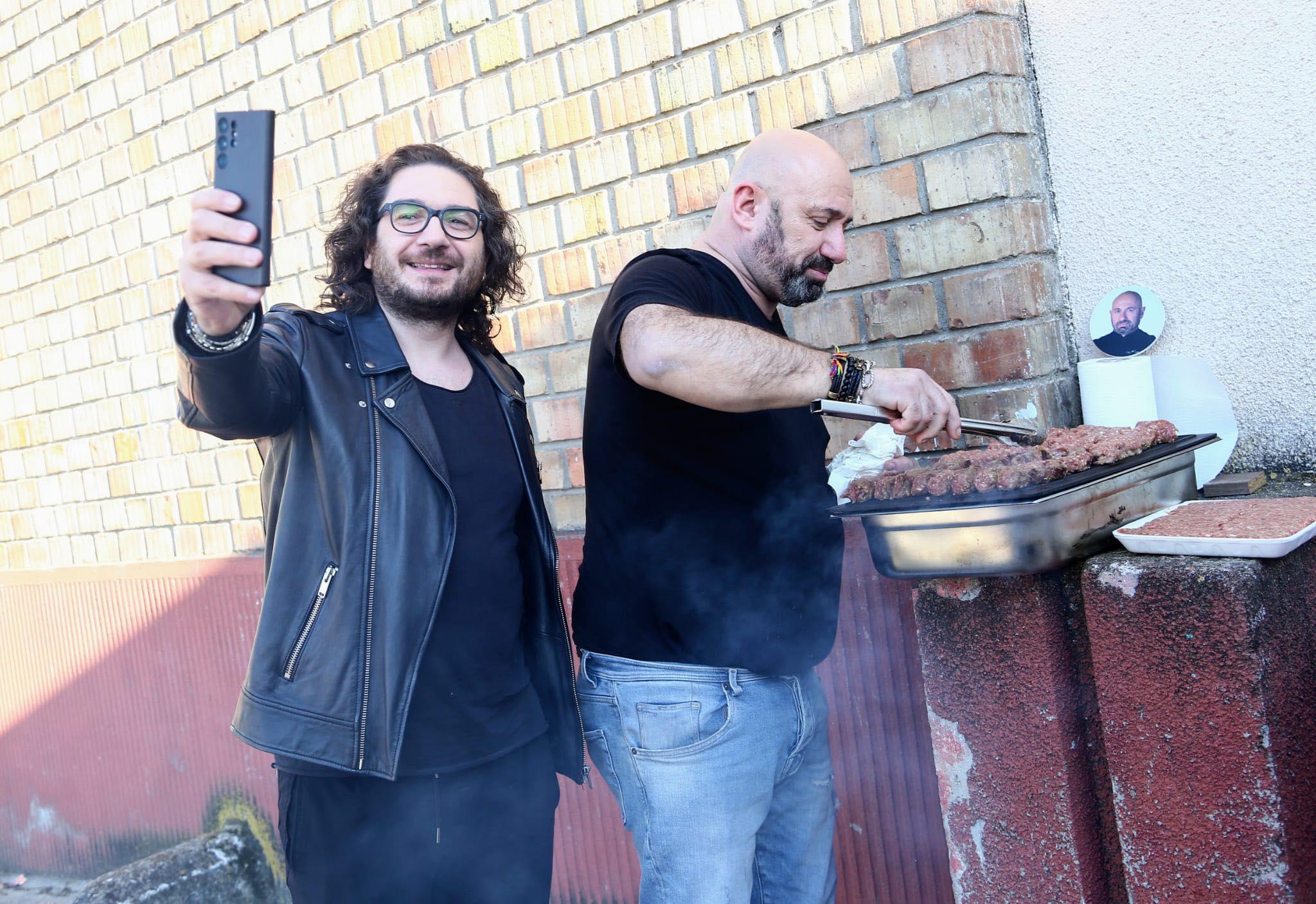 Chef Florin Dumitrescu își face selfie cu Chef Cătălin Scărlătescu care face mici pe grătar