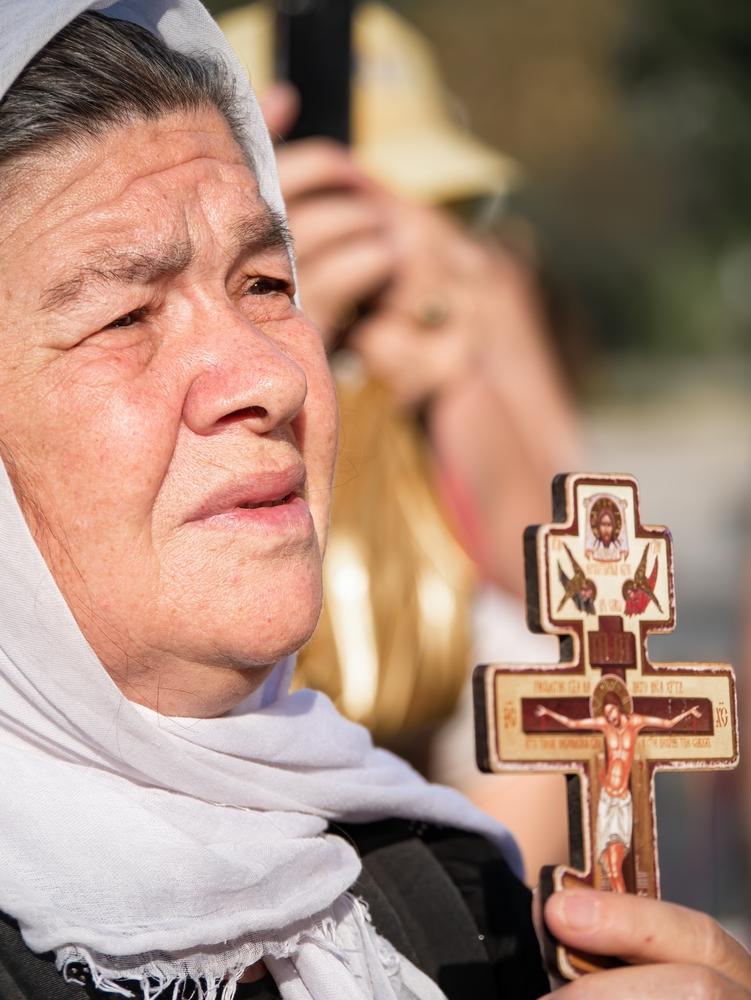 femeie in varsta cu o cruce in mana stanga