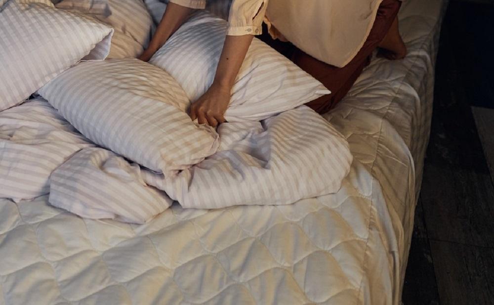 femeie in pat, cu perne si cearsaf