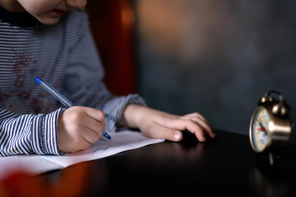 imagine cu un baiat care scrie o scrisoare