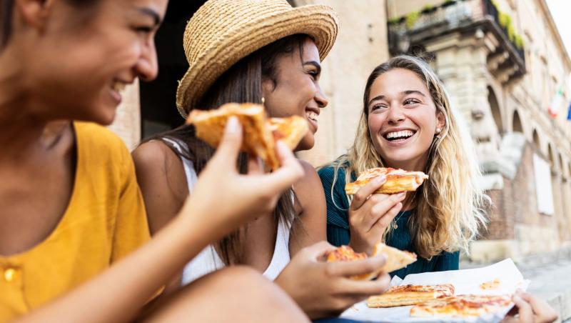 trei fete mancand pizza pe scari in italia