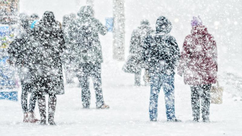 fotografie cu oameni acoperiti de zapada care merg pe strazile din bucuresti unde ninge