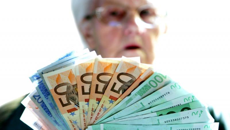 foto cu o femeie iesita la pensie care tine bani in mana
