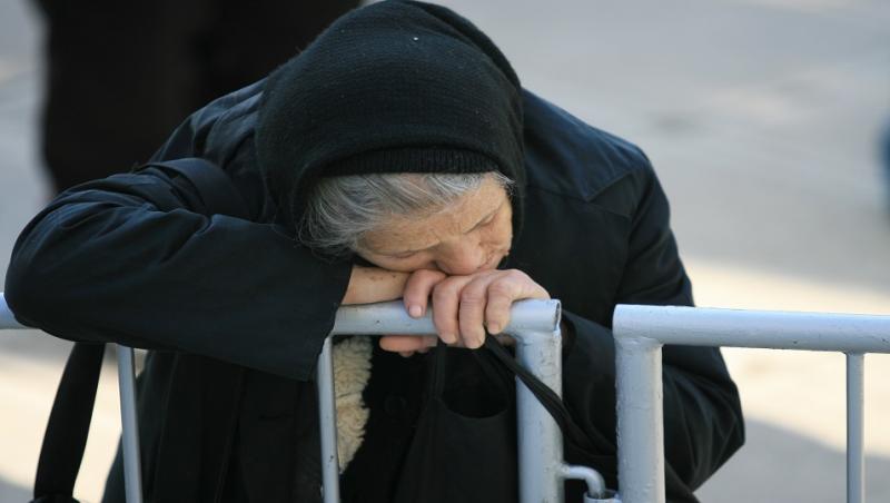 Bătrânică obosită care se sprijină de gard la evenimentul Sfântei Parascheva