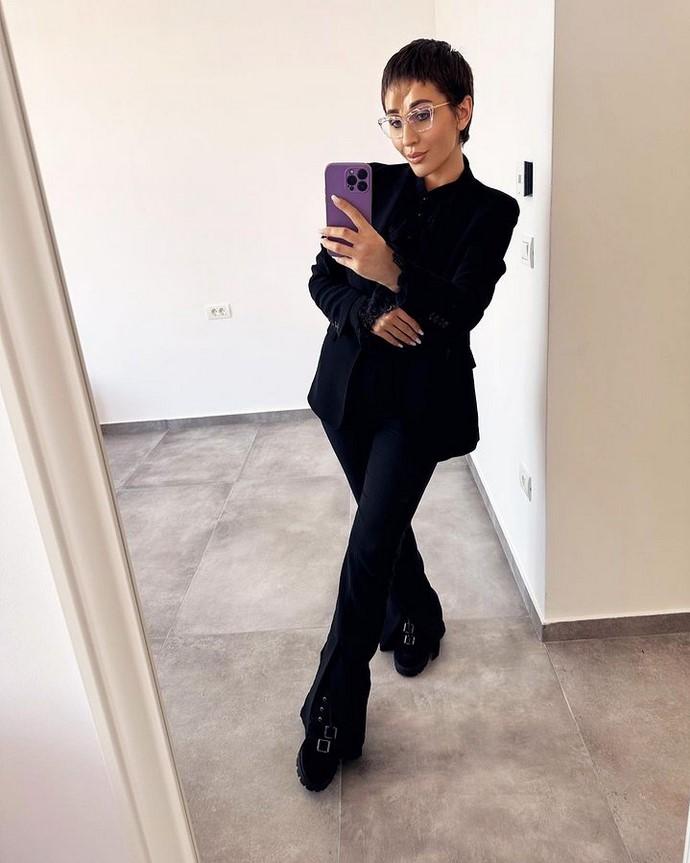 Daniela Roba pozează din cap până în picioare în oglindă purtând un costum negru elegant.