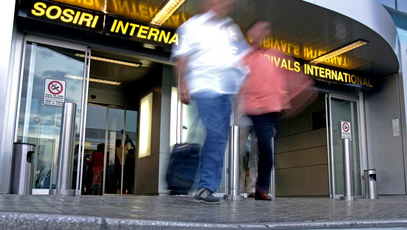 Imagine în care doi oameni părăsesc zona de sosiri a Aeroportului Internaţional Henri Coandă București
