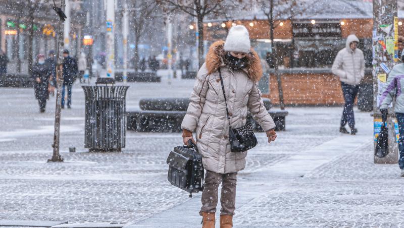 O doamnnă surprinsă de ninsoare în timp ce se plimbă