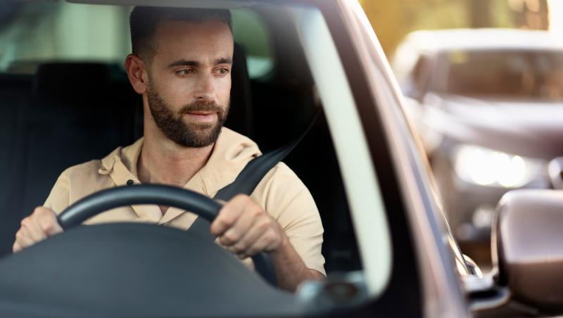 Imagine cu un șofer care se asigură în oglindă pentru a putea efectua o manevră în siguranță.