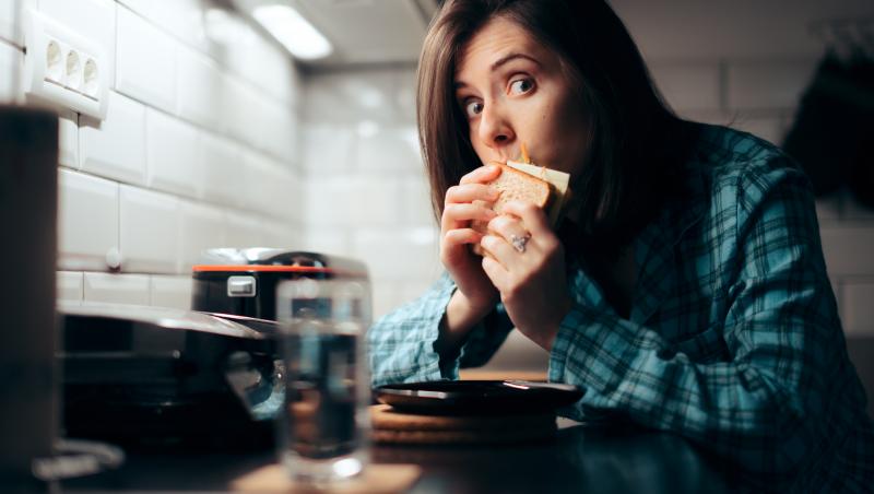 Imagine cu o femeie care mânâncă pâine pe timpul nopții pe ascuns.