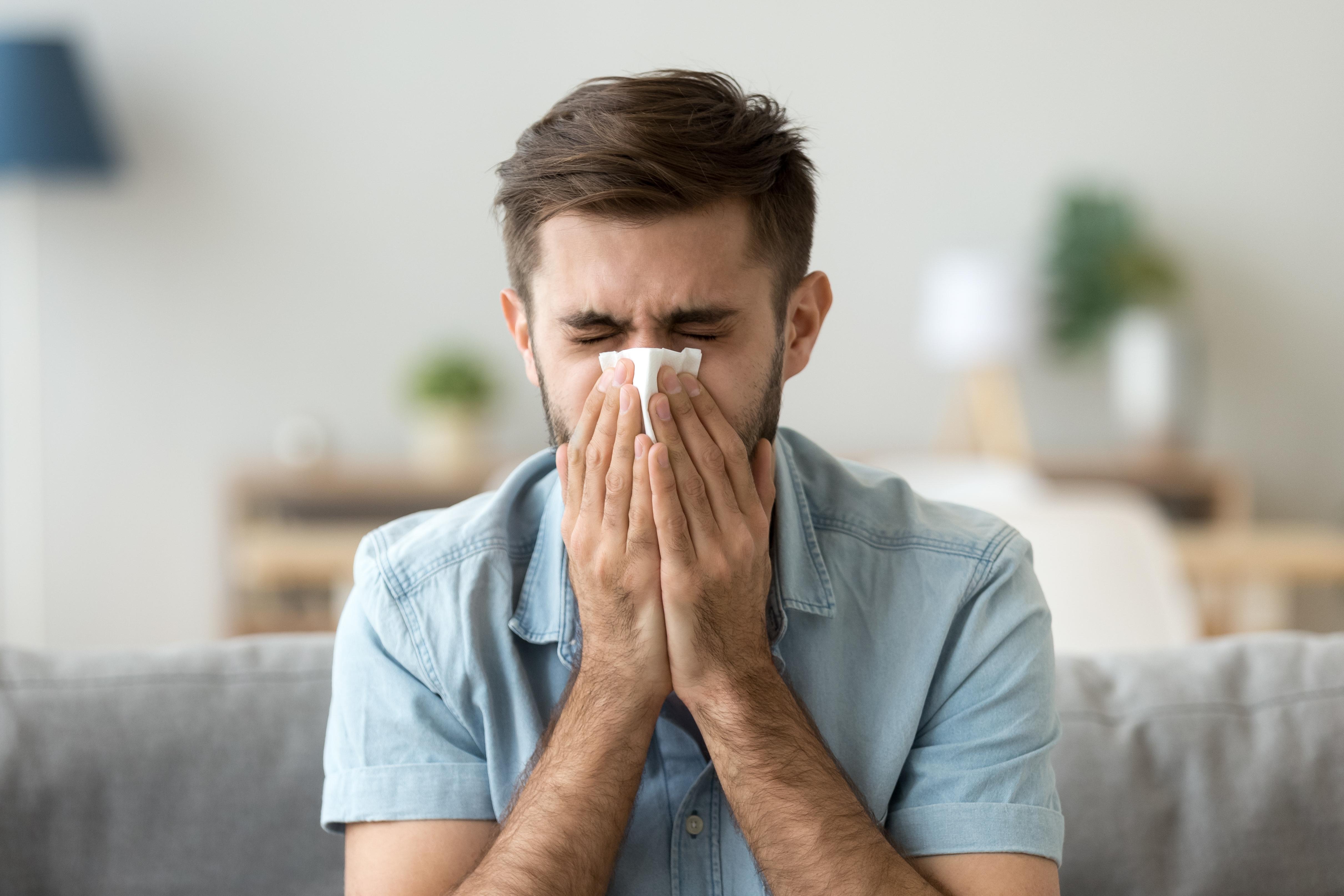 Imagine cu un bărbat care își suflă nasul din cauza alergiei la mucegai.