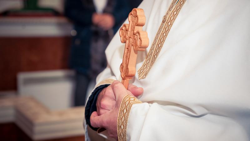Imagine cu un preot care ține o cruce în mână.