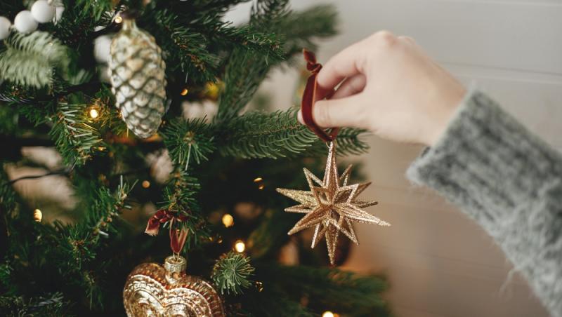 mână de femeie care agață un ornament de Crăciun într-un brad împodobit