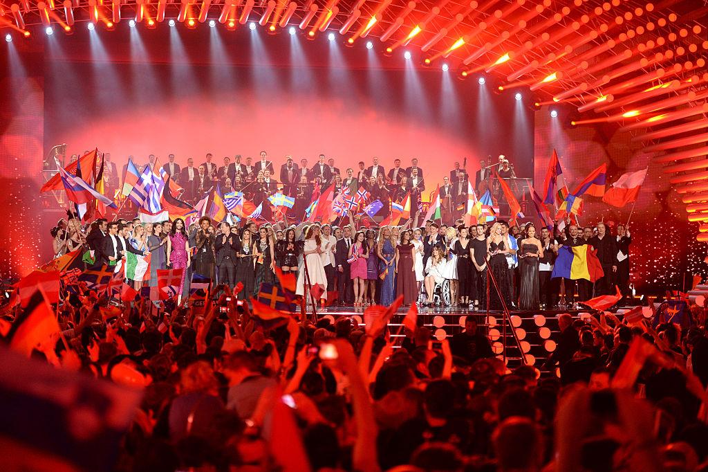 fEurovision 2015 finală, concurenții pe scenă într-o lumină roșie și apare și steagul României