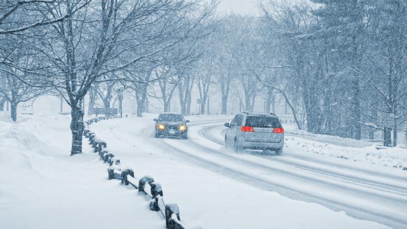 imagine cu doua masini iarna pe o strada plina cu zapada