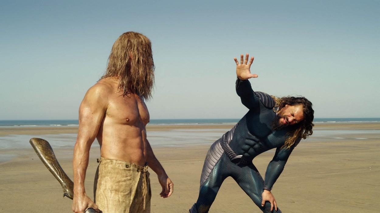 Jason Mamoa și alt actor din Aquaman pe o plajă
