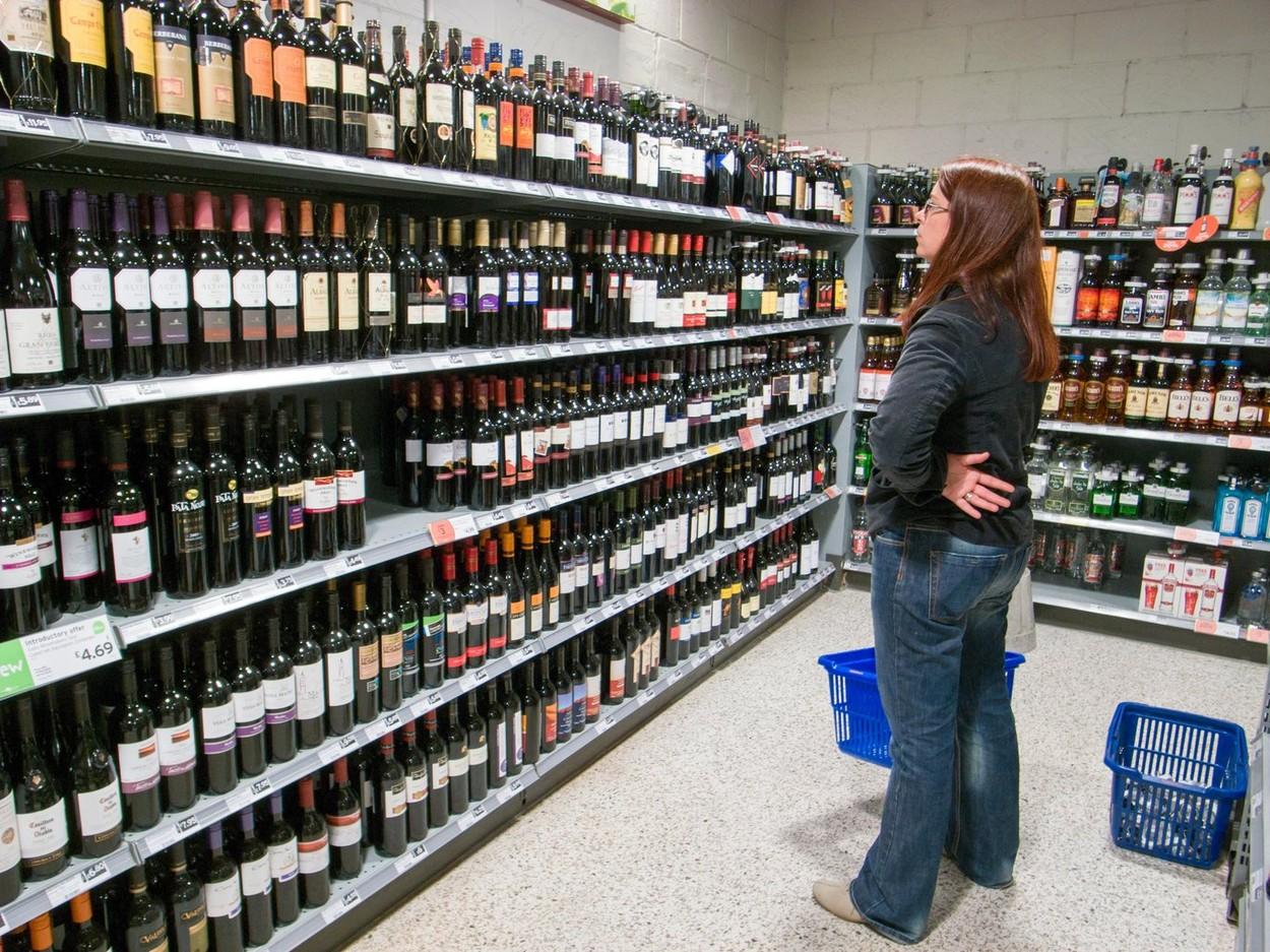 femeie care se uita la sticla de vin pentru a alege una, intr-un magazin