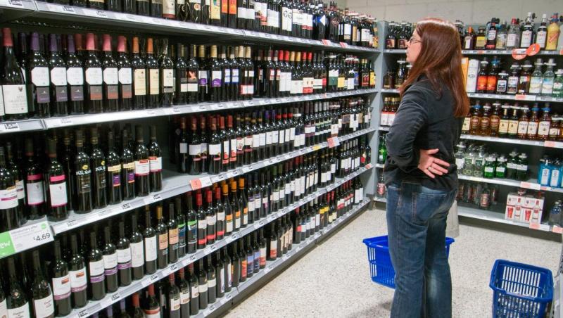 femeie care se uita la sticla de vin pentru a alege una, intr-un magazin
