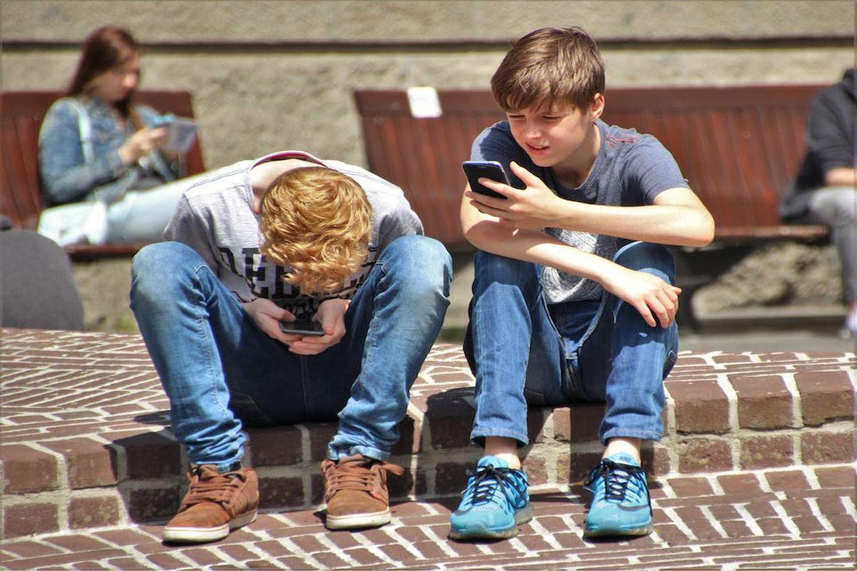 Doi copii care stau pe o bordură de ciment