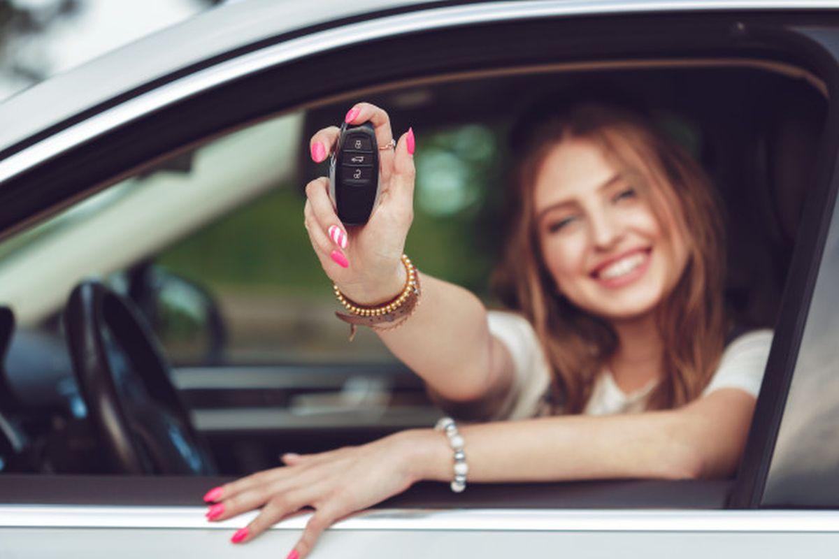 imagine cu o femeie stand la volanul unei masini