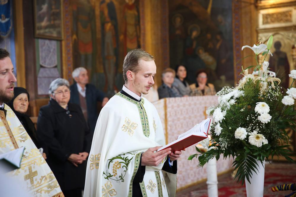 preot care citeste din cartea sfanta cu enoriasii in spate