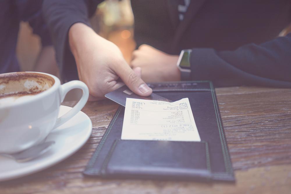imagine cu mana unui barbat platind nota de plata la un restaurant
